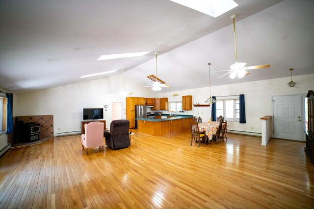 living area with a ceiling fan, a skylight, a baseboard radiator, and light wood-type flooring