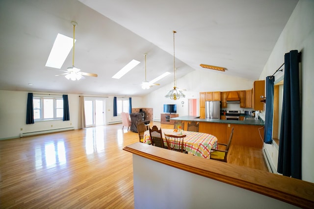 kitchen with ceiling fan, a skylight, appliances with stainless steel finishes, brown cabinets, and open floor plan