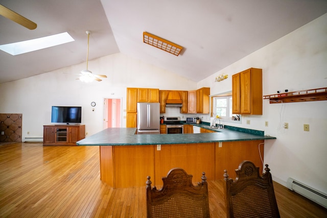 kitchen featuring dark countertops, baseboard heating, a baseboard heating unit, appliances with stainless steel finishes, and a skylight