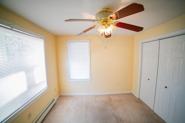 unfurnished bedroom with baseboard heating, baseboards, light carpet, and a closet