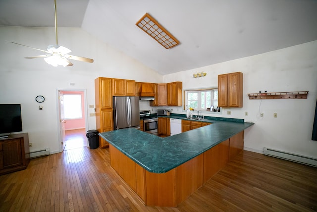 kitchen with brown cabinets, a sink, baseboard heating, stainless steel appliances, and a peninsula