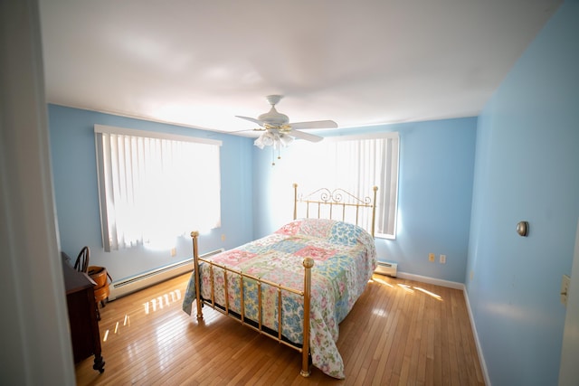 bedroom with ceiling fan, baseboard heating, hardwood / wood-style flooring, baseboards, and a baseboard heating unit