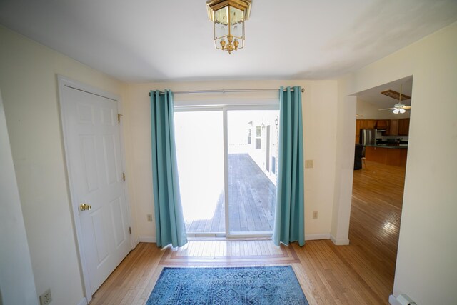 entryway featuring baseboards, a notable chandelier, and light wood-style floors