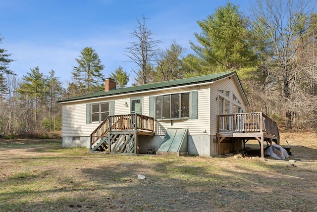 view of front of property with a deck, a chimney, and metal roof