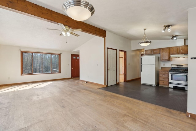 kitchen featuring stainless steel gas stove, freestanding refrigerator, baseboards, vaulted ceiling with beams, and under cabinet range hood