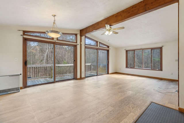unfurnished living room featuring ceiling fan, baseboards, heating unit, vaulted ceiling with beams, and wood finished floors