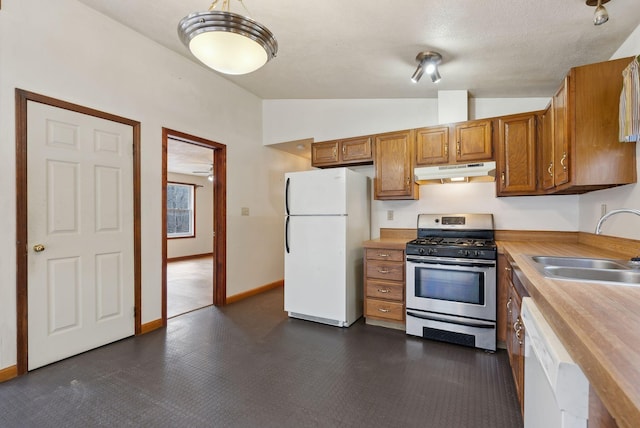 kitchen with brown cabinetry, a sink, lofted ceiling, under cabinet range hood, and white appliances