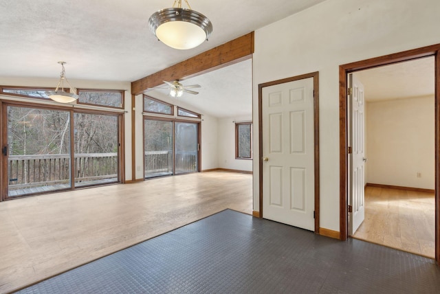 unfurnished living room featuring a ceiling fan, baseboards, plenty of natural light, and vaulted ceiling with beams