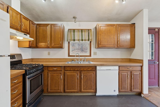 kitchen featuring white appliances, brown cabinets, under cabinet range hood, and a sink