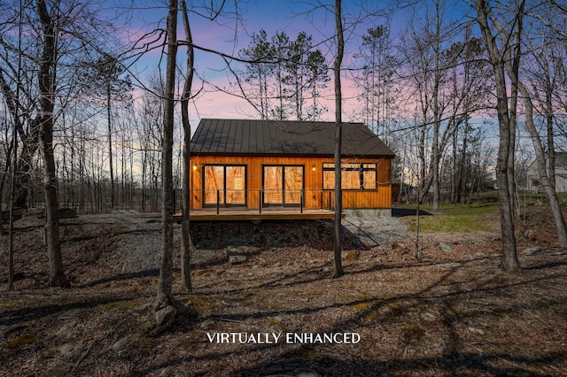 back of property at dusk featuring a standing seam roof and metal roof