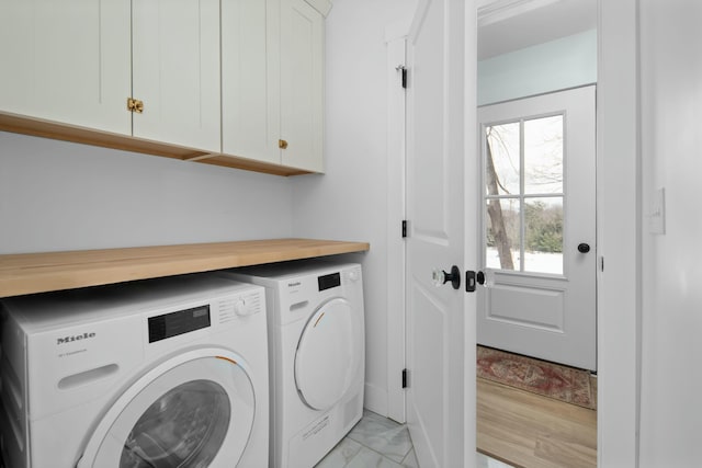 clothes washing area with marble finish floor, independent washer and dryer, and cabinet space