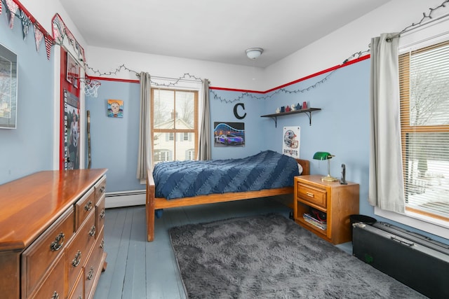 bedroom with a baseboard heating unit and hardwood / wood-style flooring