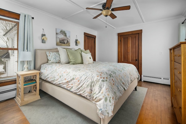 bedroom with hardwood / wood-style floors, baseboard heating, a ceiling fan, and crown molding
