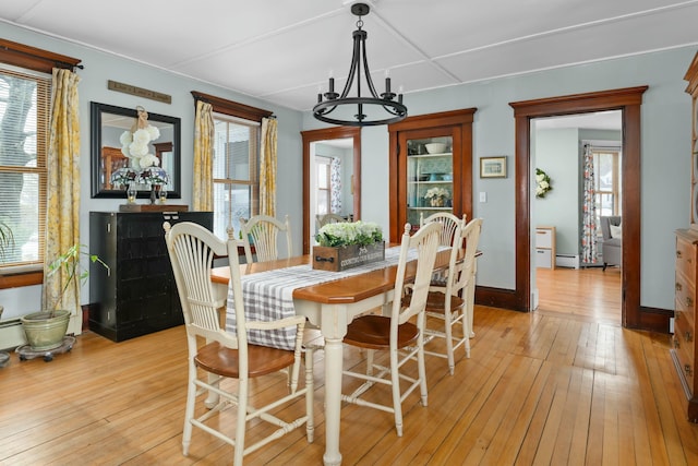 dining area featuring a healthy amount of sunlight, light wood finished floors, and an inviting chandelier