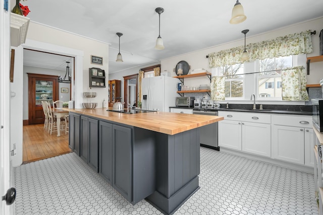 kitchen featuring stainless steel dishwasher, open shelves, butcher block countertops, white refrigerator with ice dispenser, and white cabinetry