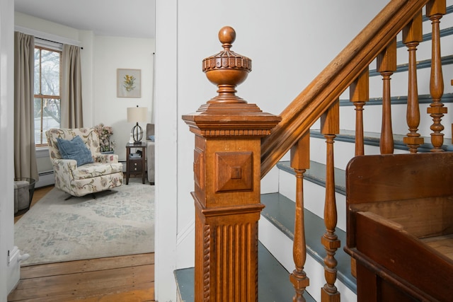 staircase with wood finished floors and a baseboard radiator