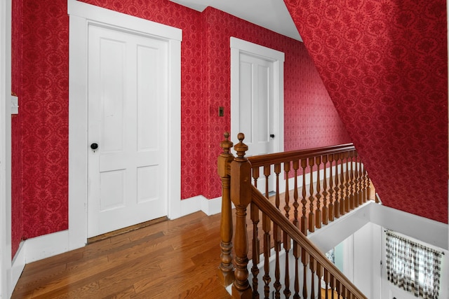 interior space featuring baseboards, wood finished floors, and wallpapered walls