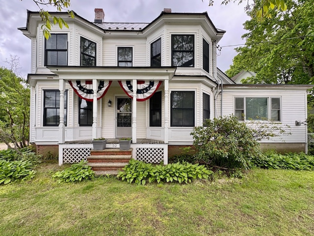 52-54 High St, North Berwick, ME 03906 - view of front facade featuring a chimney, covered porch, a front yard, and metal roof