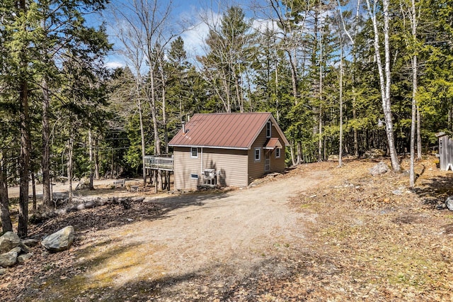 76 Cottage Shore Dr, Holden, ME 04429 - view of side of property featuring dirt driveway, metal roof, a deck, and a forest view