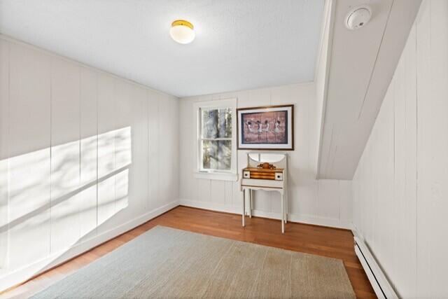 5 Paddy Creek Rd Unit 5, Kennebunkport, ME 04046 - unfurnished room featuring a baseboard radiator, wood finished floors, a smoke detector, and a decorative wall