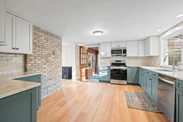 5 Paddy Creek Rd Unit 5, Kennebunkport, ME 04046 - kitchen with stainless steel appliances, light wood finished floors, plenty of natural light, white cabinetry, and brick wall