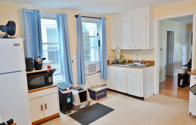 28 Cutts St, Biddeford, ME 04005 - kitchen featuring freestanding refrigerator, black microwave, white cabinets, crown molding, and light flooring