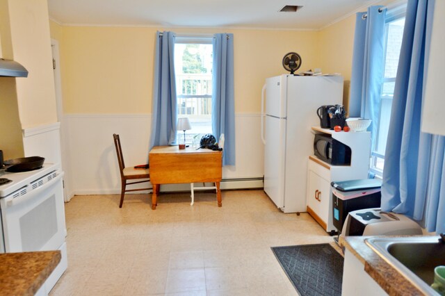 28 Cutts St, Biddeford, ME 04005 - kitchen featuring white appliances, crown molding, light floors, wall chimney exhaust hood, and a baseboard heating unit