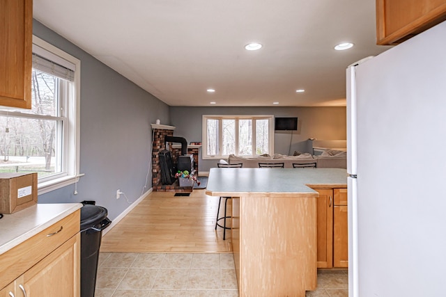 kitchen featuring freestanding refrigerator, a healthy amount of sunlight, and a wood stove