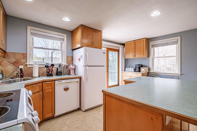 kitchen featuring white appliances, recessed lighting, brown cabinets, tasteful backsplash, and a sink