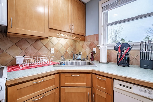 kitchen featuring light countertops, tasteful backsplash, a sink, and dishwasher