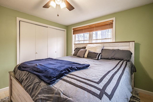 bedroom with baseboards, ceiling fan, wood finished floors, and a closet