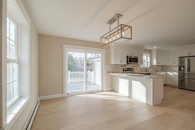 48 Highland Ave, Scarborough, ME 04074 - kitchen with light countertops, decorative backsplash, light wood-style flooring, appliances with stainless steel finishes, and baseboard heating