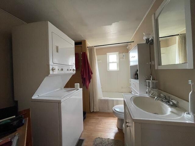 full bathroom featuring vanity, toilet, wood finished floors, stacked washer and clothes dryer, and shower / bath combination with curtain