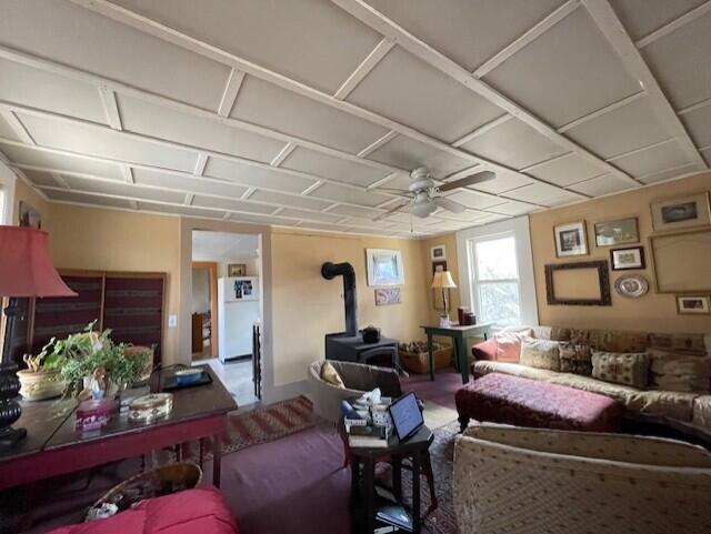 living area with ceiling fan and a wood stove