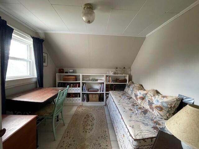 interior space featuring lofted ceiling, crown molding, and tile patterned floors