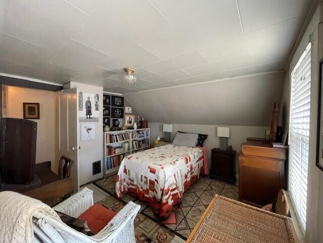 bedroom with lofted ceiling, attic access, and multiple windows