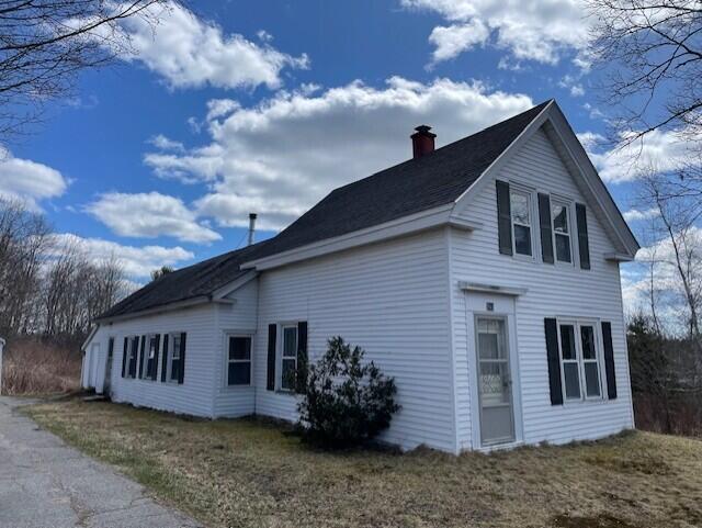 view of property exterior featuring a chimney and a yard