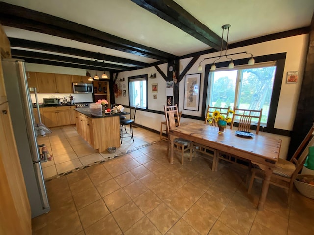 1361 Pleasant St, Blue Hill, ME 04614 - kitchen with stainless steel appliances, dark countertops, light tile patterned floors, beam ceiling, and a center island