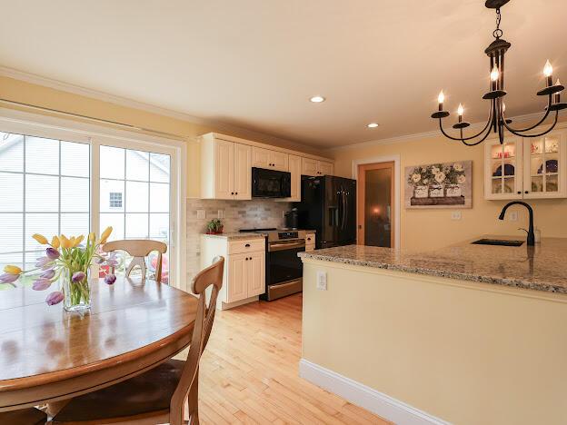 14 Connor Dr Unit 14, Gorham, ME 04038 - kitchen featuring decorative backsplash, a sink, black appliances, light wood-style floors, and ornamental molding