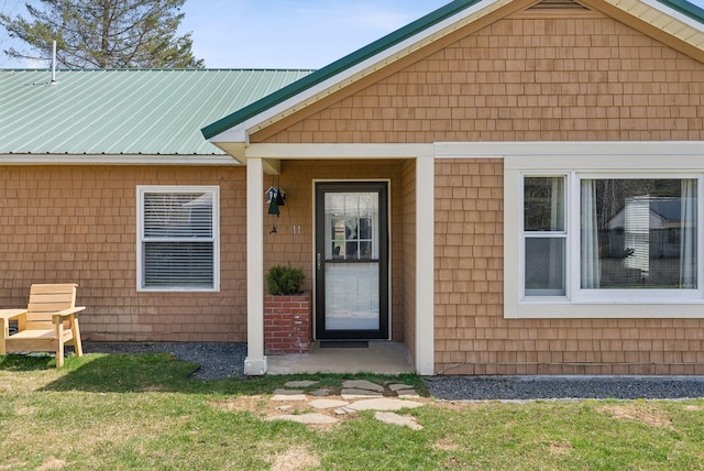 doorway to property with metal roof and a yard