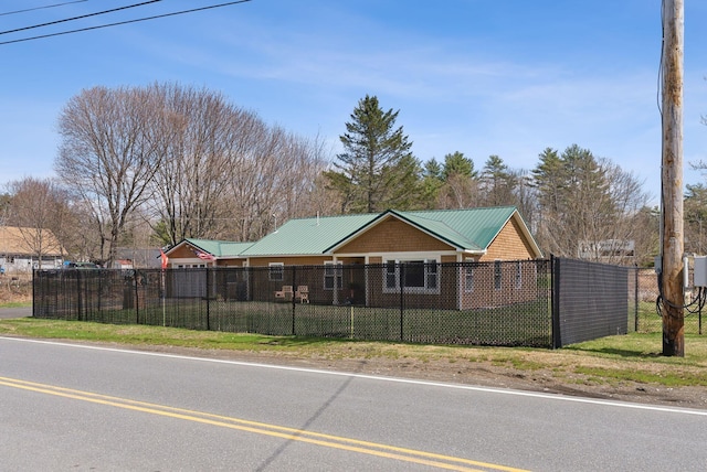 single story home with a fenced front yard, metal roof, and a front yard