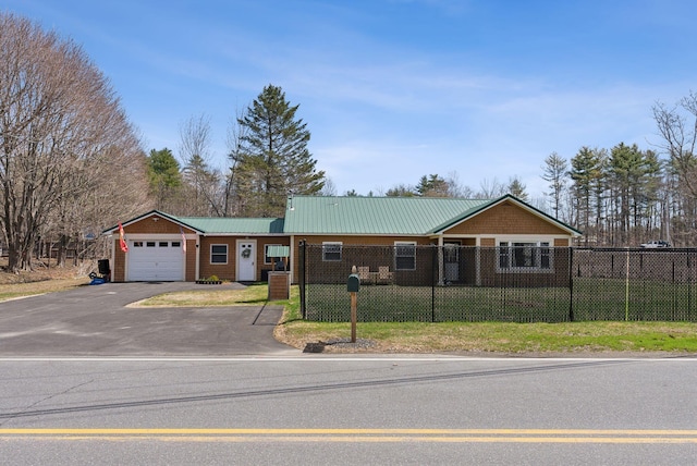 ranch-style house with a fenced front yard, metal roof, a garage, driveway, and a front lawn