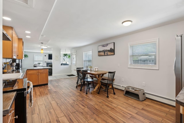 dining area featuring ornamental molding, a baseboard heating unit, light wood-style flooring, and baseboards