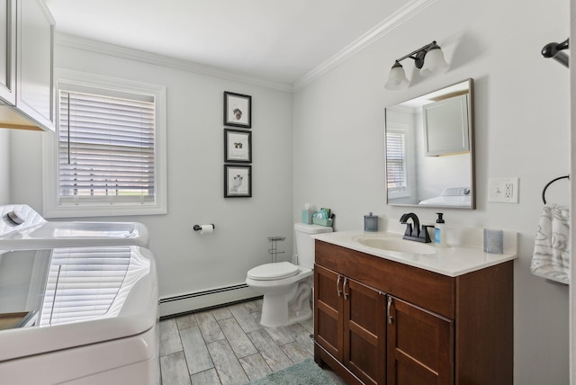 half bathroom with washing machine and clothes dryer, crown molding, wood tiled floor, a baseboard heating unit, and toilet