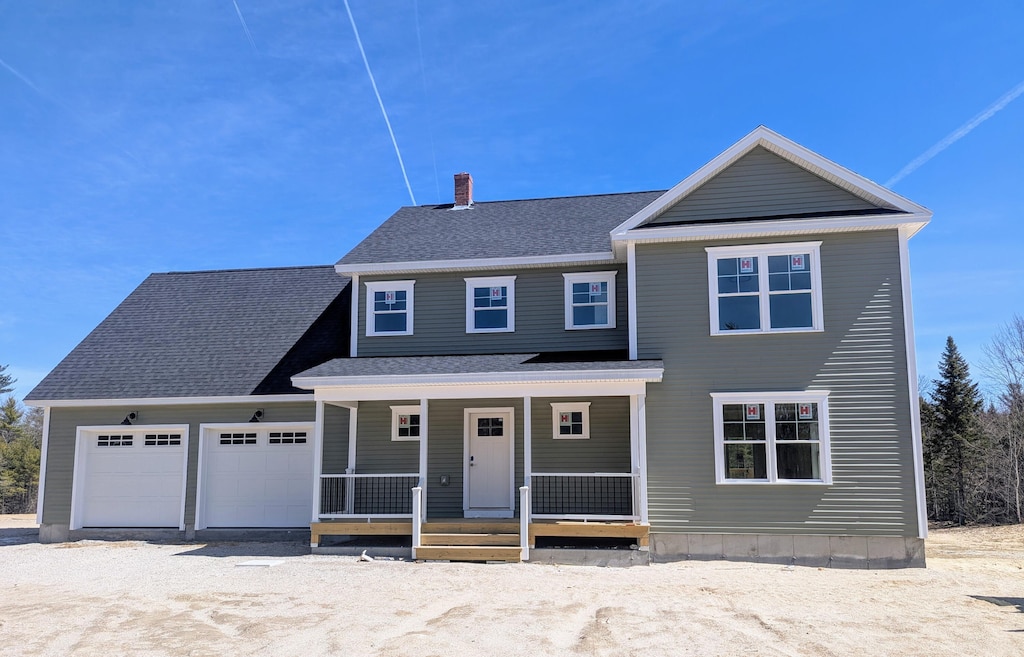 view of front facade featuring a chimney, an attached garage, a shingled roof, and covered porch