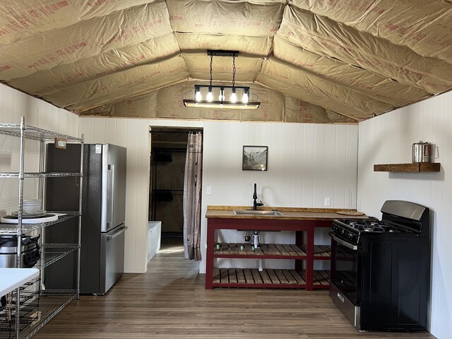 kitchen featuring vaulted ceiling, black gas stove, a sink, dark wood-style flooring, and freestanding refrigerator
