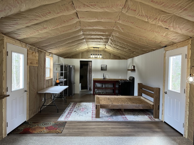 bedroom featuring lofted ceiling, wood finished floors, and freestanding refrigerator