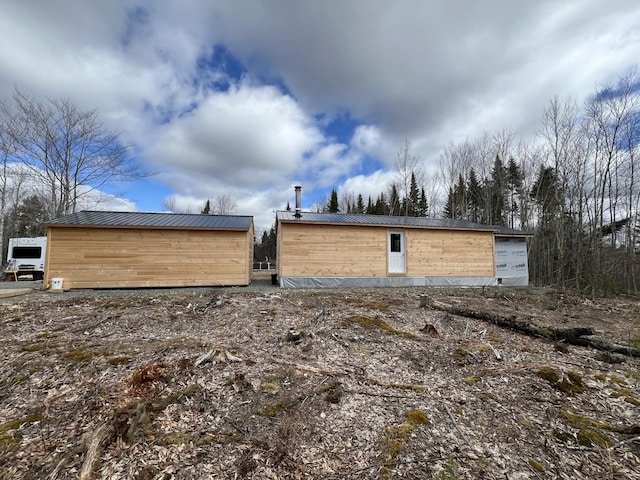 back of property featuring an outbuilding and metal roof