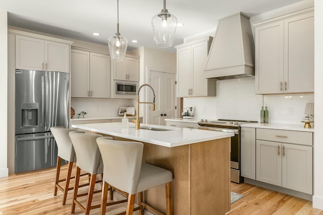 37 Cascade Cir Unit 26, Kennebunk, ME 04043 - kitchen with stainless steel appliances, a sink, custom exhaust hood, light countertops, and an island with sink