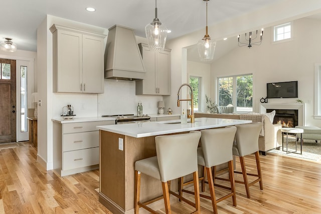 37 Cascade Cir Unit 26, Kennebunk, ME 04043 - kitchen with custom exhaust hood, a sink, a wealth of natural light, a center island with sink, and light countertops